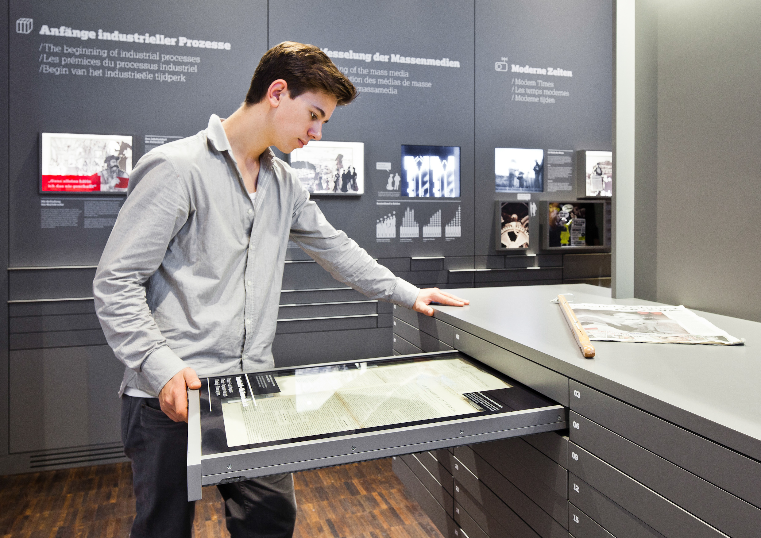 Ein Besucher des Internationalen Zeitungsmuseums liest sich die Inhalte einer Zeitungsschublade durch